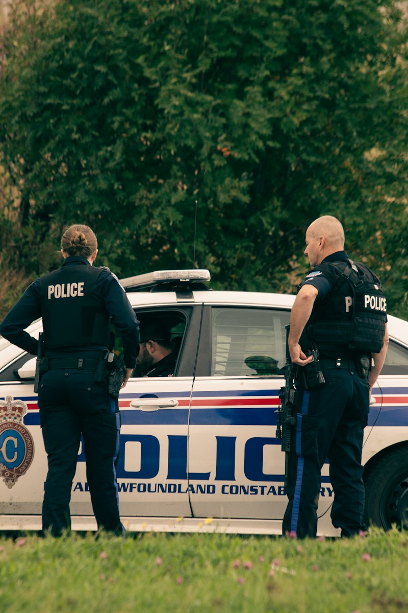 2 police men standing on white police car during daytime