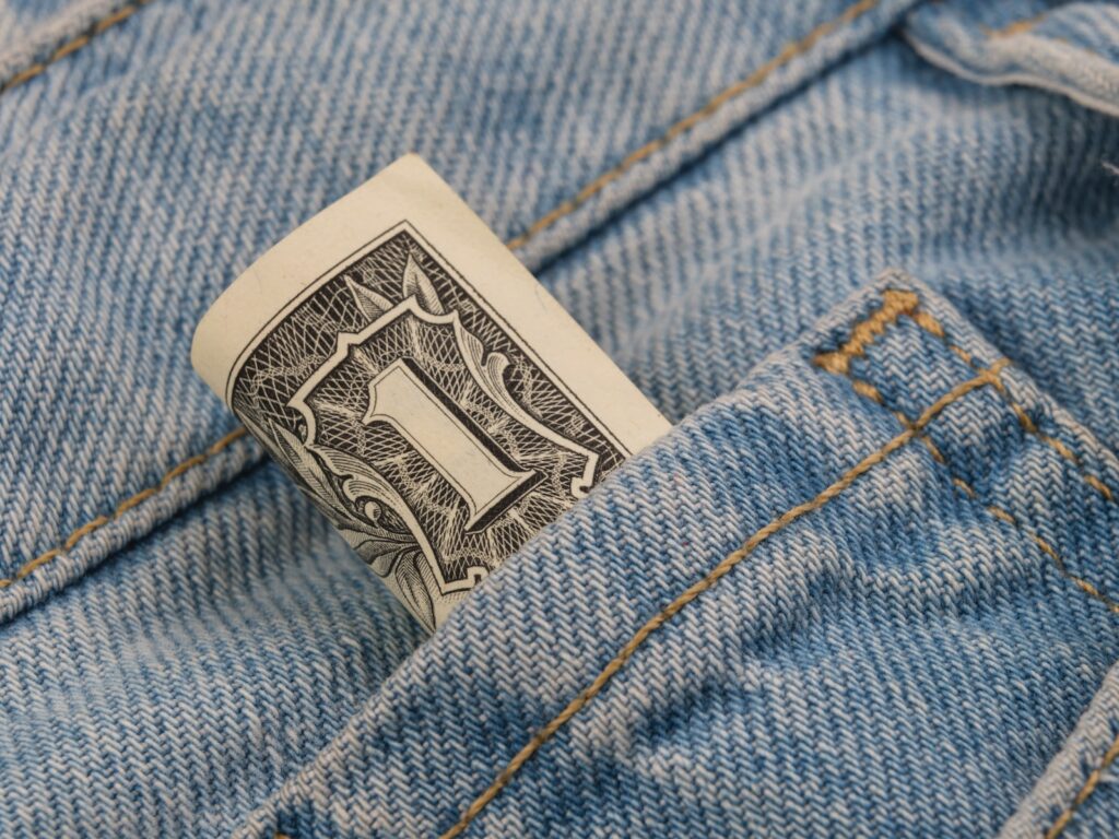 a dollar bill sticking out of the back pocket of a pair of jeans