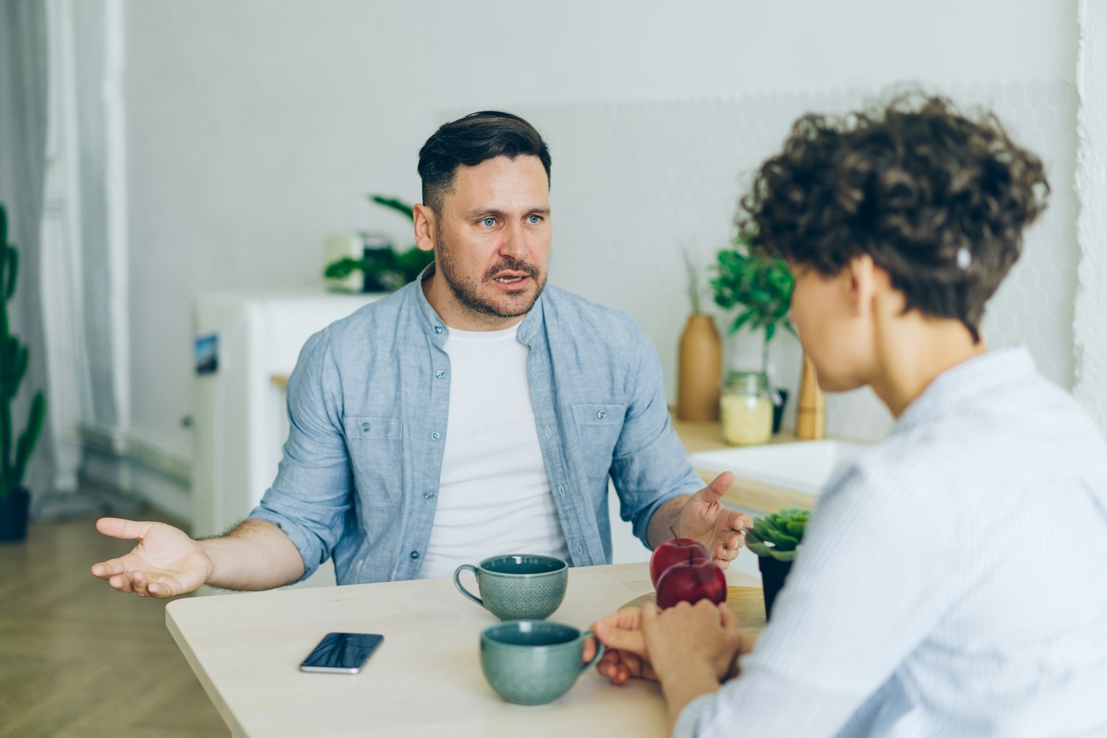 a man sitting at a table talking to a woman